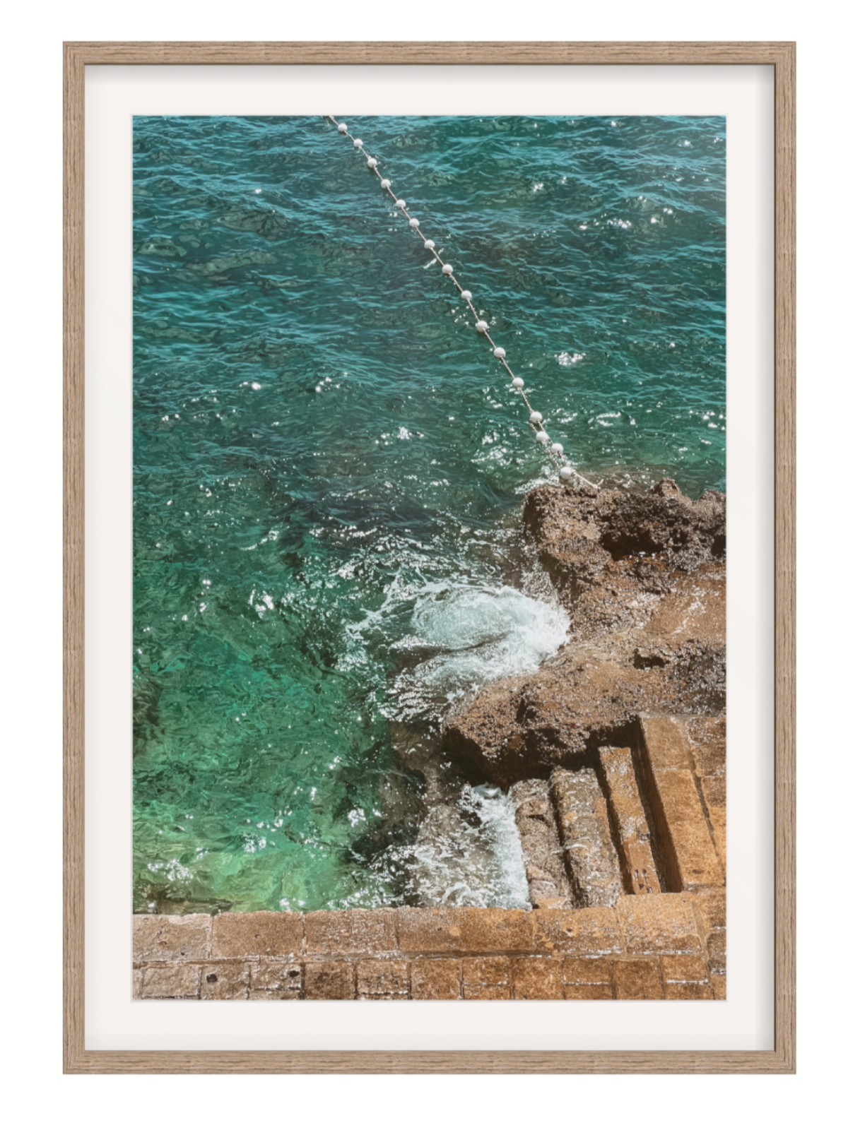 Framed photograph of ocean waves crashing against a rocky shore. hazel frame with border