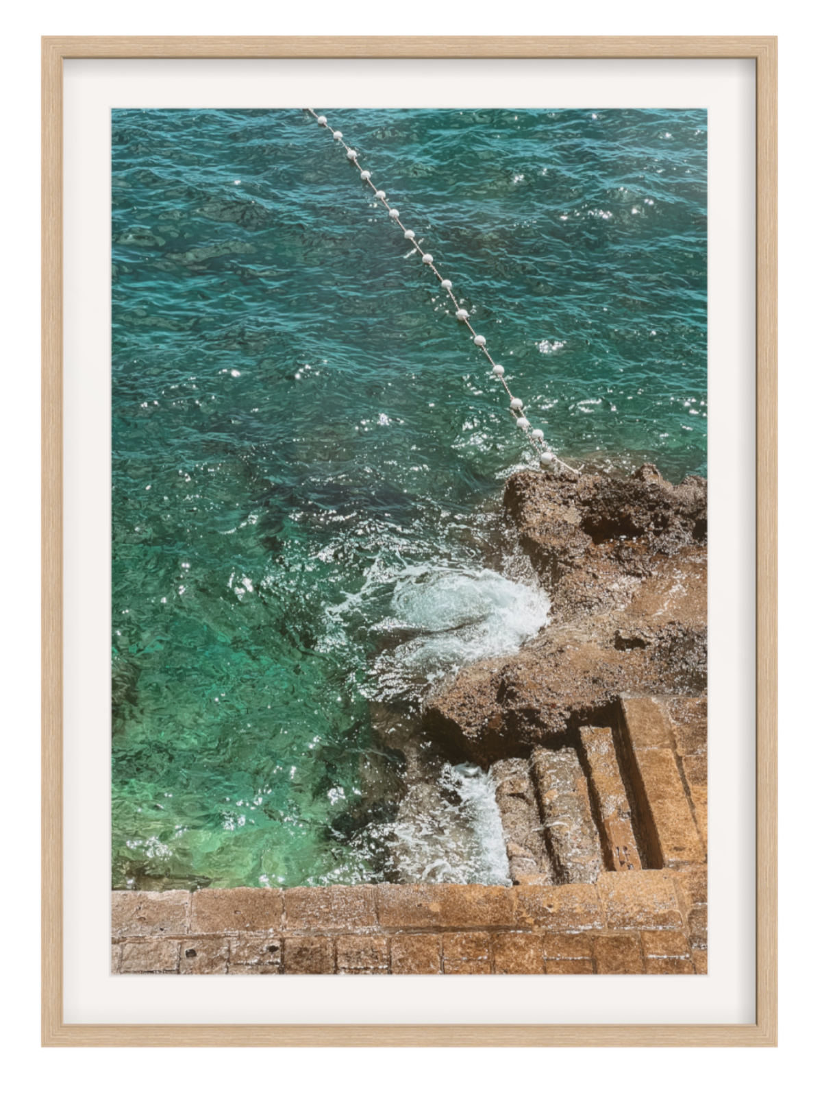 Framed photograph of ocean waves crashing against a stone wall. oak frame with border