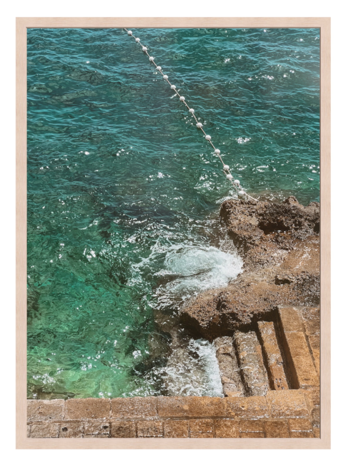Framed photograph of ocean waves crashing against rocks with a wooden light oak frame.