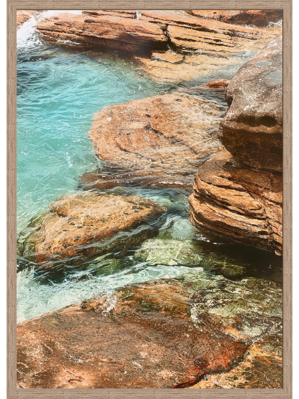 Framed photograph of a rocky coastal scene with clear blue water.