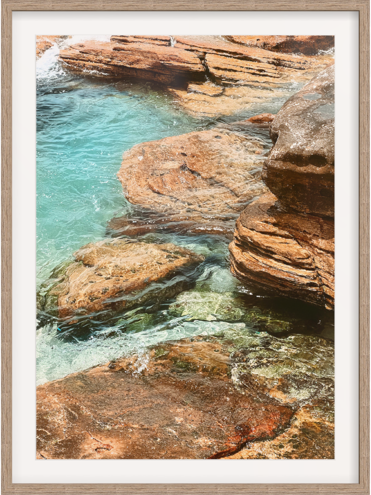 Framed photograph of a rocky coastal scene with clear blue water.